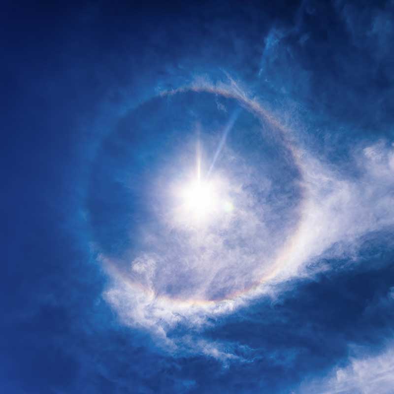 A bright sun with a circular halo effect graces the blue sky, its presence as clear and insightful as an intuitive reading amidst the wispy clouds.